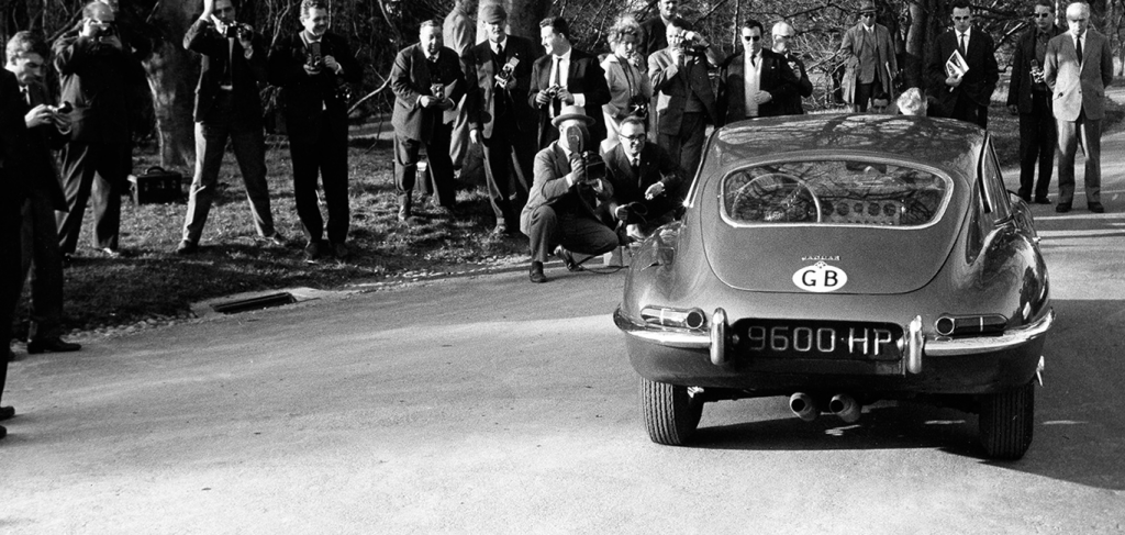 The press gathers around the Jaguar E-Type at its 1961 unveiling by Lake Geneva