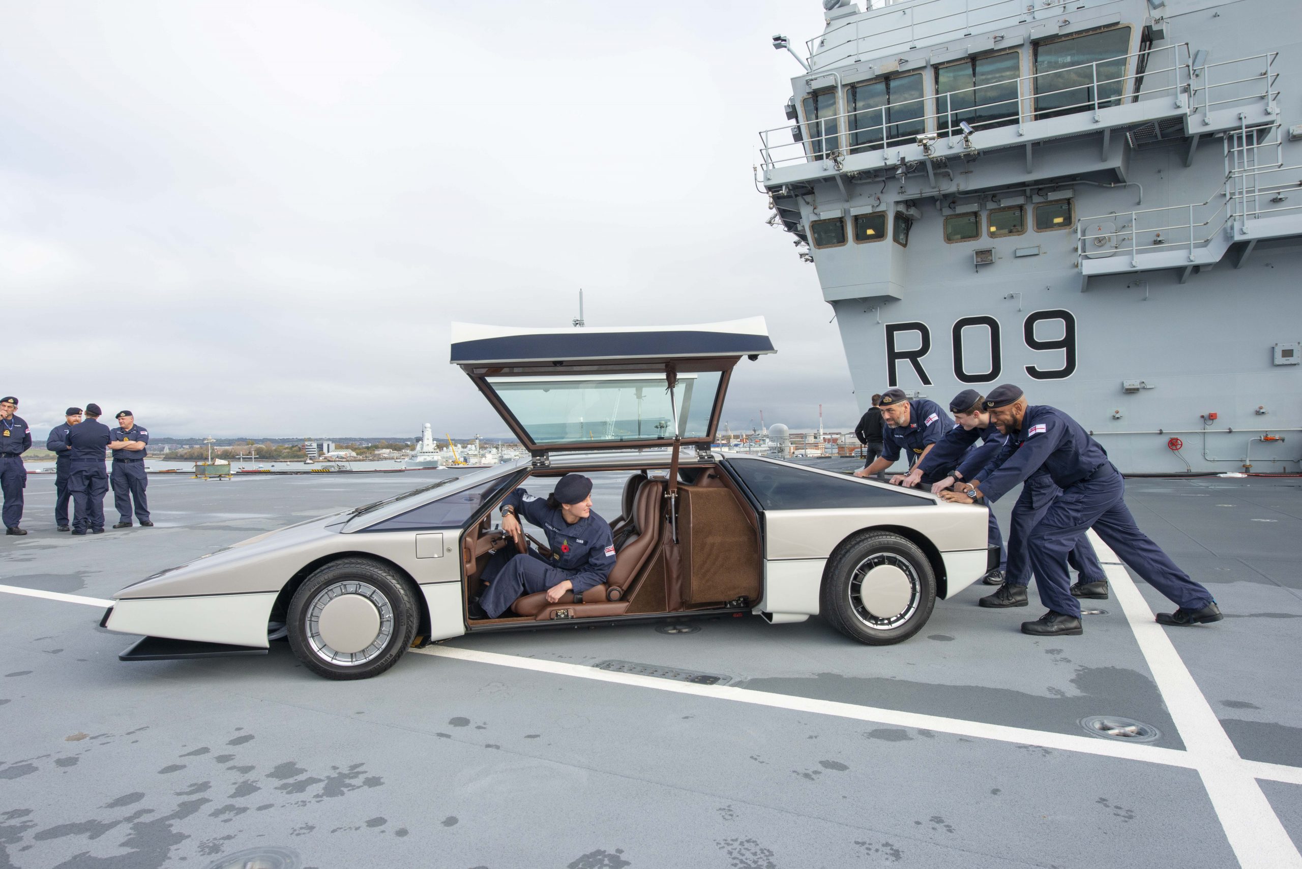 Crew members of the HMS Prince of Wales pushing the Aston Martin Bulldog