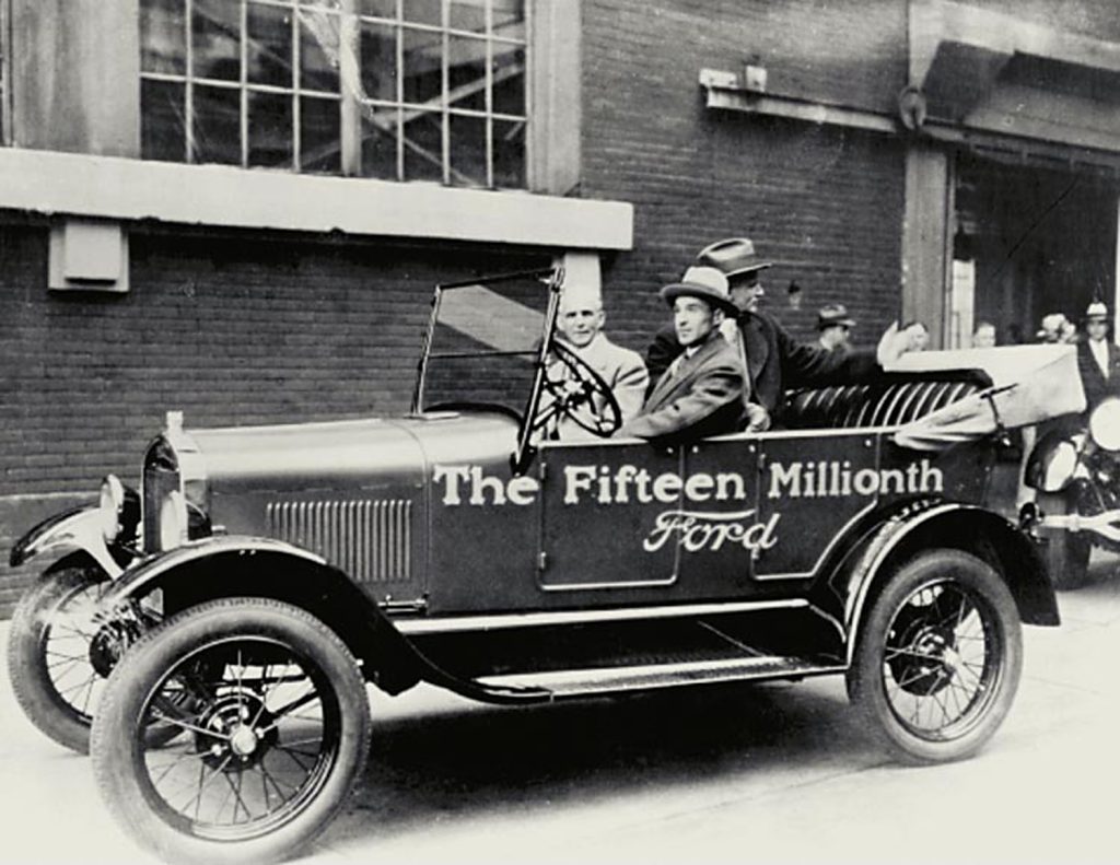 Edsel Ford drives his father, Henry, out of the Ford Highland Park Plant in the very last Model T ever made.