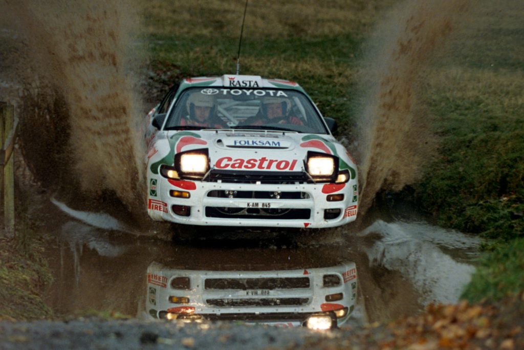 Juha Kankkunen drives his Toyota through a large puddle