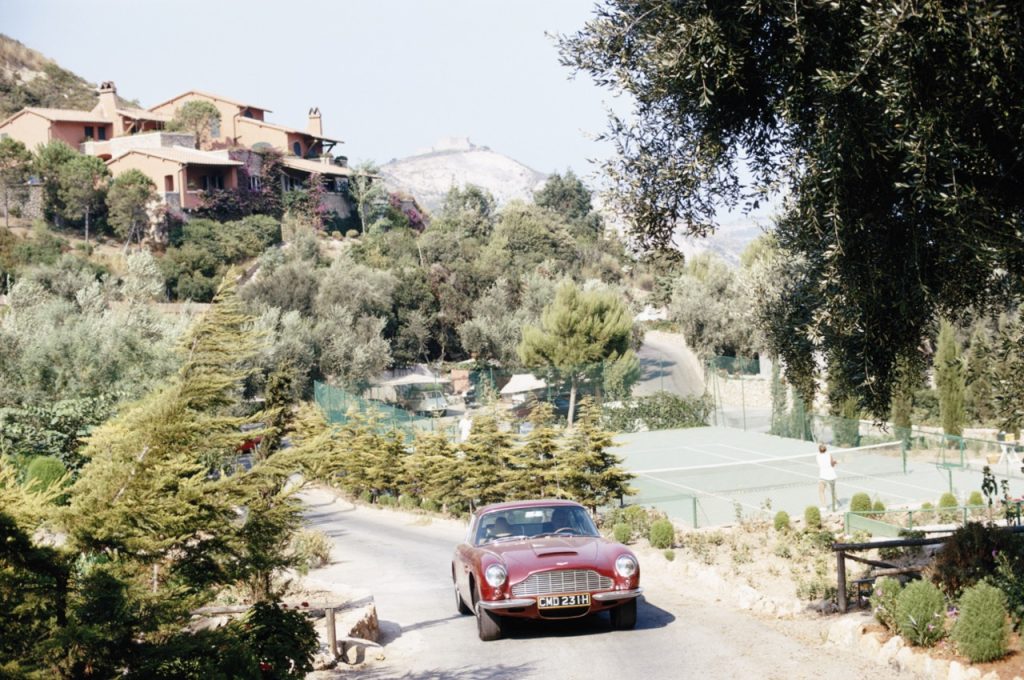 Aston Martin DB6 sports car driving past the tennis courts